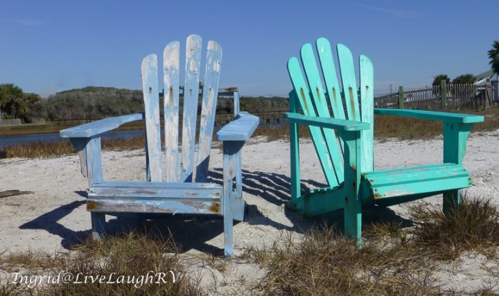 two aged adirondack chairs on a lone beach